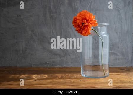 Stillleben im rustikalen Stil mit Glasvase und roten Mohnblumen auf einem Holztisch Stockfoto