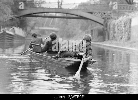 London, England, um 1967. Drei Jungen des Pirates’ Club paddeln mit einem Boot entlang des Regent’s Canal in der Nähe des Cumberland Basin. In der Ferne sind eine Fußgängerbrücke und die Snowdon Aviary des Londoner Zoos im Regent’s Park zu sehen. Der Pirates’ Club, ein Kinderbootclub, wurde 1966 in Gilbey’s Wharf am Regent’s Canal in der Nähe von Camden, London, gegründet. Ihr Klubhaus war ein alter Lastkahn und eine Reihe kleiner Boote und Kanus wurden für die Kinder gespendet. Stockfoto