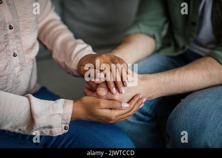 Die junge afroamerikanische Ärztin, die beim Treffen die Hände des Patienten in der Hand hält, unterstützt den Patienten Stockfoto