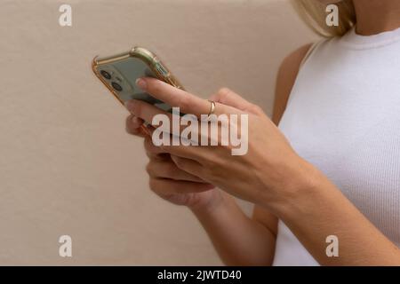 Nahaufnahme der Hände einer nicht erkennbaren blonden Frau, die ein Mobiltelefon benutzt. Konzept der unabhängigen Geschäftsfrau und Nutzung von Technologie. Stockfoto