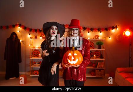 Fröhliches junges Paar, das mit ihrer Jack-o-Laterne in gruselige Halloween-Kostüme gekleidet ist Stockfoto