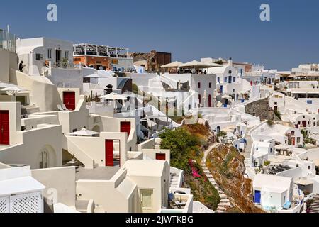 Oia, Santorini, Griechenland - Juni 2022: Traditionelle weißgetünchte Gebäude mit Terrassen und Terrassen mit Blick auf das Meer in Oia Stockfoto