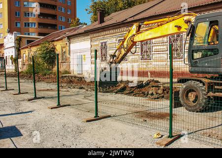 Aushubarbeiten. Der Eimer des Traktors lädt den Boden mit einer Schaufel in die Rückseite eines Muldenkipper auf der Baustelle. Stockfoto