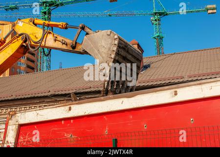 Aushubarbeiten. Der Eimer des Traktors lädt den Boden mit einer Schaufel in die Rückseite eines Muldenkipper auf der Baustelle. Stockfoto