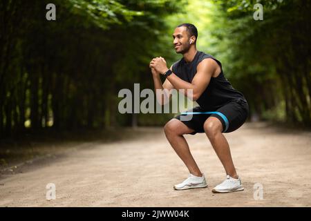 Motivierter muskulöser schwarzer Mann, der im Park mit Band trainiert Stockfoto