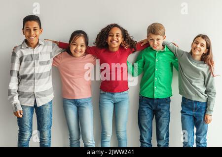 Fröhliche Multiethnische Kinder Umarmen Sich Und Lächeln Vor Camera Indoors Stockfoto