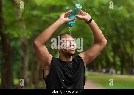 Müde schwarz Kerl Jogger spritzt Wasser auf seinen Kopf Stockfoto