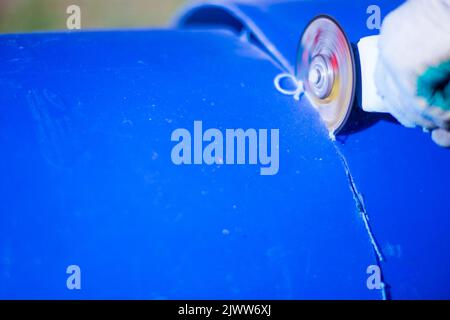 Mann, der mit der Schleifsäge arbeitet, Nahaufnahme des Werkzeugs. Elektrische Säge und Hände von Arbeitern mit Funken. Arbeiter schneidet mit Schleifer Stockfoto