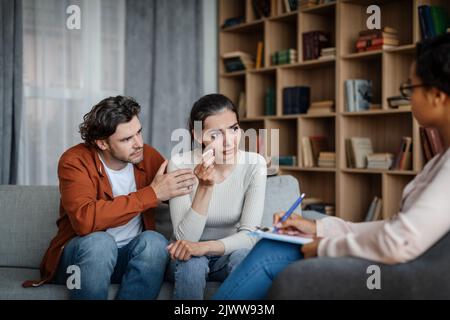 Unglücklicher, trauriger, tausendjähriger Kaukasianer beruhigt die weinende Frau beim Treffen mit dem Psychologen im Büro Stockfoto