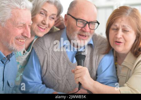 Zwei ältere Paare singen Karaoke mit Mikrofon Stockfoto
