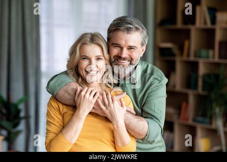 Portrait Von Liebenden Ehegatten Mittleren Alters, Die Kamera Umarmen Und Lächeln Stockfoto