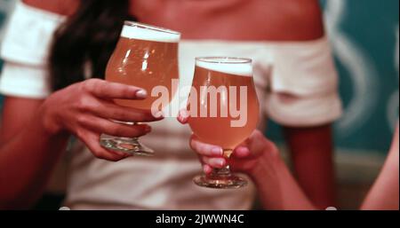 Zwei weibliche Hände klirren Bier vom Fass Stockfoto