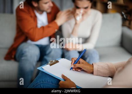 Trauriger junger europäischer Kerl beruhigt weinende Frau beim Treffen mit Psychologen im Inneren der Büroklinik, aus nächster Nähe Stockfoto
