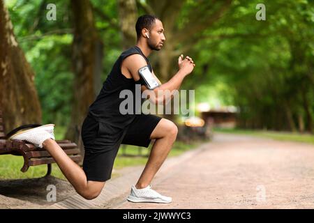 Motivierter muskulöser schwarzer Mann, der im Park trainiert, Seitenansicht Stockfoto