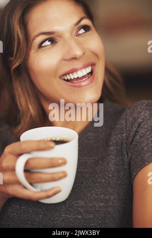 Der Morgen ist gebrochen und der Kaffee hat gesprochen. Eine junge Frau genießt zu Hause eine Tasse Kaffee. Stockfoto