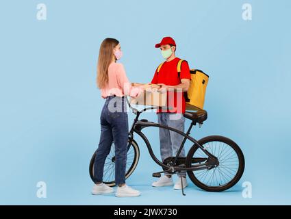 Kurier Mann Liefert Karton An Lady Auf Blauem Hintergrund Stockfoto