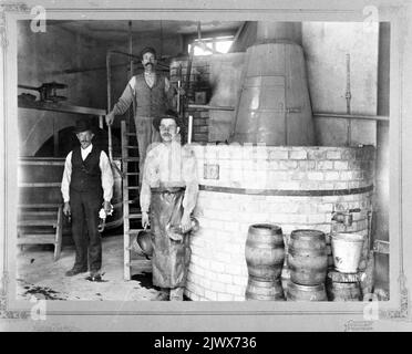 Interieur der Wilanders Brauerei und der Softdrink-Fabrik in Ådala, Kvistholmen. Der Mann in einem Hut auf der linken Seite kann der Mann mit einem Notizbuch an der Flasche sein, siehe Bild XLM.A 15-15. Interieur från Wilanders Bryggeri och Läsketrycksfabrik på Ådala, Kvistholmen. Mannen i hatt till vänster kan vara mannen med anteckningsbok vid buteljtappningen, se bild XLM.A 15-15. Stockfoto