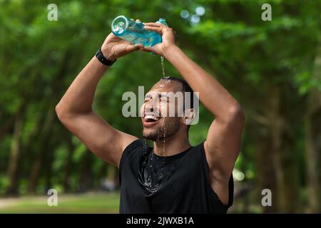 Heißer afroamerikanischer Sportler, der Wasser auf den Kopf spritzt Stockfoto