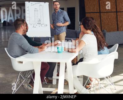 Der kreative Prozess. Ein reifer Mann, der Kollegen in einem Büro eine Whiteboard-Präsentation gibt. Stockfoto