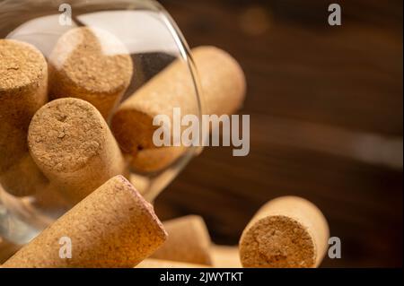 Ein Weinglas und Weinstopfen auf einem Holztisch. Nahaufnahme, selektiver Fokus. Stockfoto