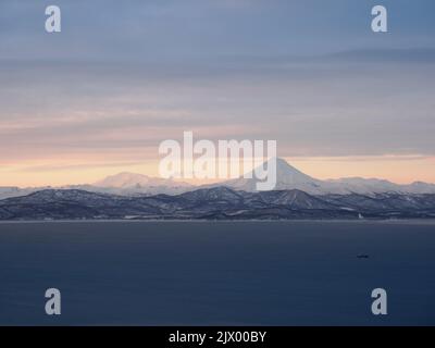 Fernansicht des Vilyuchik stratovulcano hinter dem Meerwasser auf einem Sonnenuntergang Stockfoto