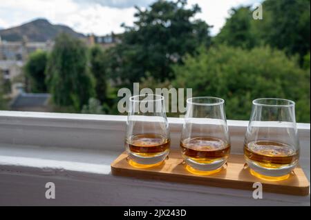 Flug von Single Malt Scotch Whisky, serviert auf einer alten Fensterbank im Scottisch House mit Blick auf den alten Teil der Stadt Edinburgh, Schottland, Großbritannien, mit einem Schluck Whisky Stockfoto