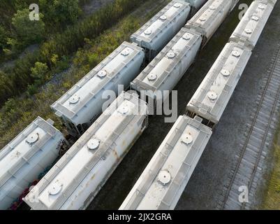 Ein Luftfoto über einem Bahnhof mit Reihen überdachter Zugwaggons in der Nähe einer Kohlebergbau- und -Verarbeitungsanlage. Stockfoto