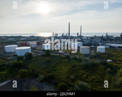 Luftaufnahme eines riesigen Feldes mit zahlreichen Öllagertanks, am Morgen gesehen. Eine große petrochemische Ölraffinerie ist im Hintergrund zu sehen. Stockfoto