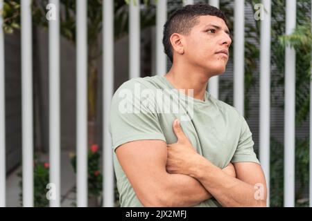 Junger Mann, der seine Hände kreuzte und zur Seite auf der Straße schaute. Stockfoto
