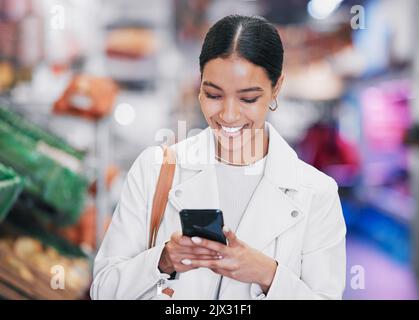Supermarkt, Telefon oder Frau mit Lächeln im Lebensmittelgeschäft, die Forschung, E-Commerce oder Online-Shopping auf gesunde Produkte. Zufriedener Kunde beim Einkaufen Stockfoto