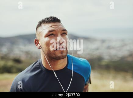 Seine Musik motiviert ihn. Ein junger Mann, der draußen läuft. Stockfoto