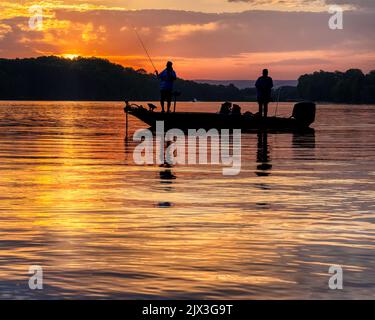 Zwei Männer Bass Fishing in einem Bass-Boot auf Tims Ford See in Tennessee mit frühen Morgensonnenaufgangssilhouette. Stockfoto