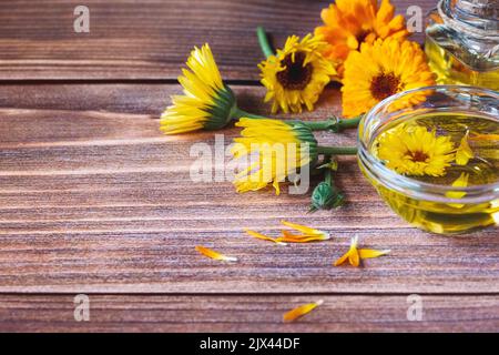 Calendula Kräuteröl aus Calendula officinalis Blumen auf Holzhintergrund, Kopierraum Stockfoto