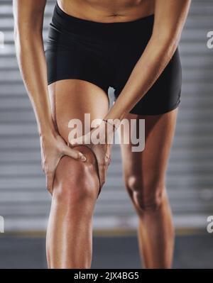 Achten Sie darauf, sich nicht zu strapazieren. Eine Sportlerin mit einer Knieverletzung. Stockfoto