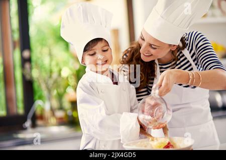 Backen ist Liebe, die essbar gemacht wird. Eine Mutter und ihr Sohn backen in der Küche. Stockfoto