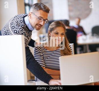 Sie liefern immer erstklassige Arbeit. Zwei Designer arbeiten an einem Computer zusammen. Stockfoto