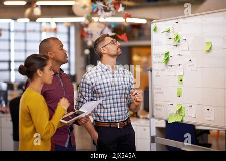 Diese Geschäftsidee sieht interessant aus. Eine Gruppe von Mitarbeitern Brainstorming an einem Whiteboard. Stockfoto