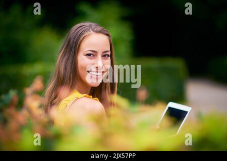 Mein Lieblingsort für ein gemütliches Stöbern. Eine junge Frau mit einem digitalen Tablet im Park. Stockfoto