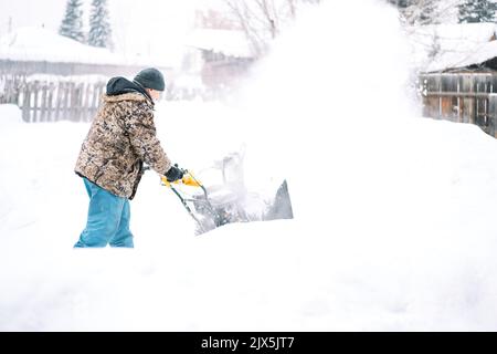 Ein Mann reinigt die Straße von Schnee mit einem Schneepflug Stockfoto