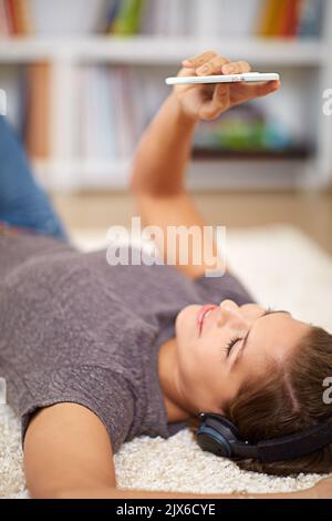 Einstieg in den Relax-Modus mit großartiger Musik. Eine junge Frau, die Musik hört, während sie sich zu Hause entspannt. Stockfoto