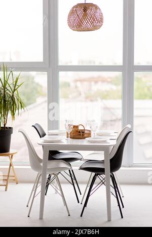 Modernes Interieur einer gemütlichen Küche im Esszimmer, weiße Möbel, vor dem Hintergrund eines Panoramafensters. Konzeptionelles Dekor, Haushypothek Stockfoto