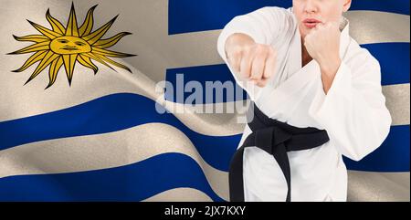 Mittelteil einer jungen Kampfkünstlerin, die mit der Faust gegen die uruguayische Flagge schlägt Stockfoto
