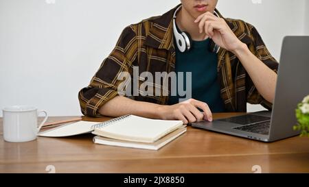 Hipster und hübscher junger asiatischer Mann, College-Student oder Büroangestellter, der seinen Projektauftrag plant und ausarbeitet Stockfoto