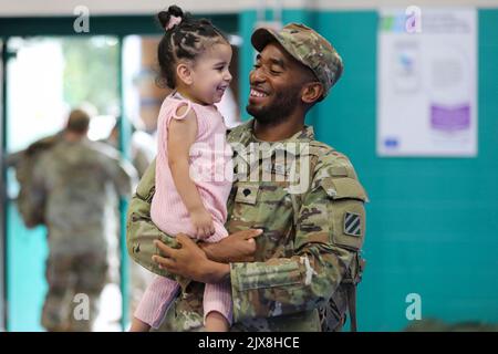 Fort Stewart, Georgia, USA. 30. August 2022. SPC der US-Armee. Joshua Milton, ein Kraftfahrzeugbetreiber, der dem Kampfteam der Panzerbrigade 1., 3. Infanterie-Division, zugeordnet ist, hält seinen dAugusthter, Malaya, nach einer Umstellungszeremonie in Fort Stewart, Georgia, im August. 29, 2022. Die Zeremonie fand im Newman Gym statt, um die Umverteilung der Soldaten der Brigade nach einem sechsmonatigen Einsatz im Trainingsgebiet Grafenwoehr zu markieren. Kredit: U.S. Army/ZUMA Press Wire Service/ZUMAPRESS.com/Alamy Live Nachrichten Stockfoto