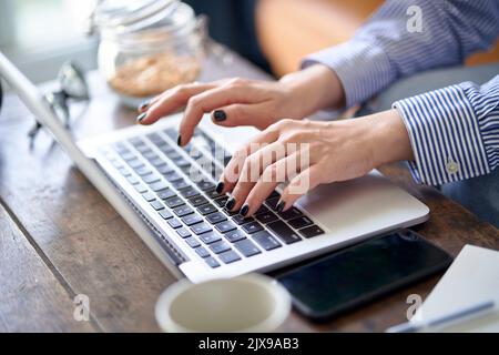 Nahaufnahme von Händen und Fingern einer asiatischen Frau, die von zu Hause aus mit einem Laptop arbeitet Stockfoto