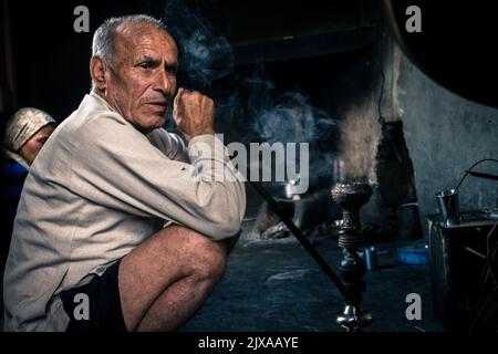 September 19. 2021 Himalaya Uttarakhand Indien. Ein alter Mann aus dem Stamm der Garhwali raucht Pfeifenhookah in seinem traditionellen Zuhause. Stockfoto