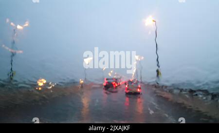 Im Auto. Nahaufnahme Regen Wassertropfen. Auto Windschutzscheibe Blick während regnerischen Tag auf der Autobahn am Abend. Stockfoto