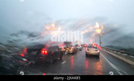 Im Auto. Nahaufnahme Regen Wassertropfen. Auto Windschutzscheibe Blick während regnerischen Tag auf der Autobahn am Abend. Stockfoto