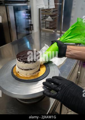 dekorator Buttercreme auf Milchkuchen mit Sahnesack auftragen Stockfoto