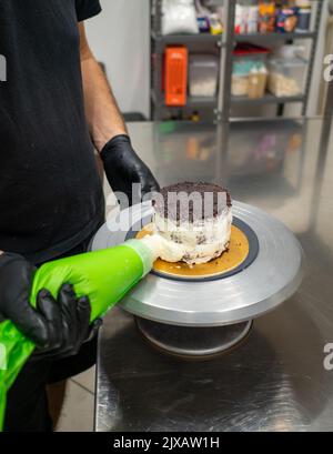 dekorator Buttercreme auf Milchkuchen mit Sahnesack auftragen Stockfoto